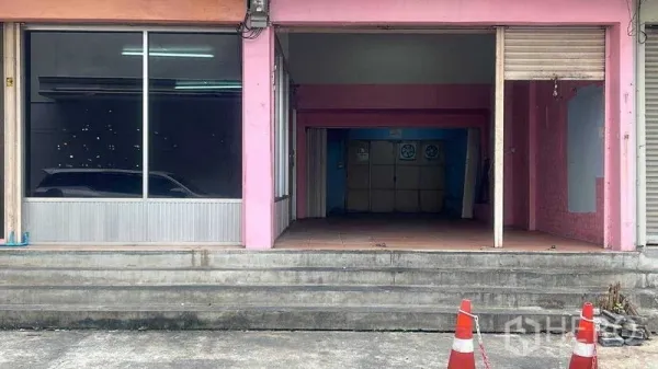 零售空间 出租在Bang Na, Bangkok - 店铺入口台阶与开放门洞，卷闸门旁为大型展示窗。