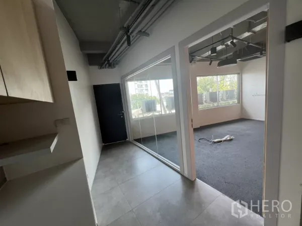 零售空间 出租在Khlong Toei, Bangkok - 走廊通向玻璃办公室，地毯地面，可见城市景观。