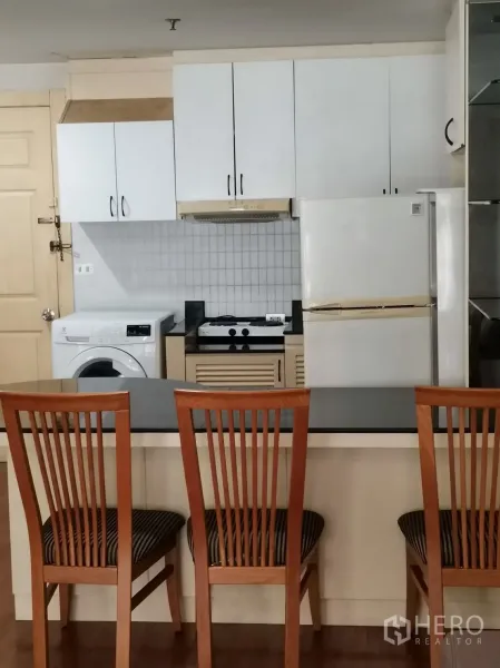 คอนโด ให้เช่าในPathum Wan, Bangkok - เคาน์เตอร์บาร์พร้อมเก้าอี้ไม้สามตัว หันเข้าหาครัวบิลท์อินที่มีเตา เครื่องดูดควัน ตู้เย็น และเครื่องซักผ้า