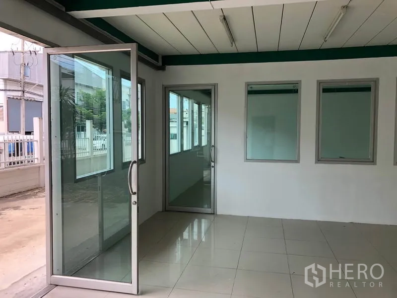 Factory for rent in Lam Luk Ka, Pathum Thani - Ground‑floor glass entry to the office area with sliding doors and tiled flooring.