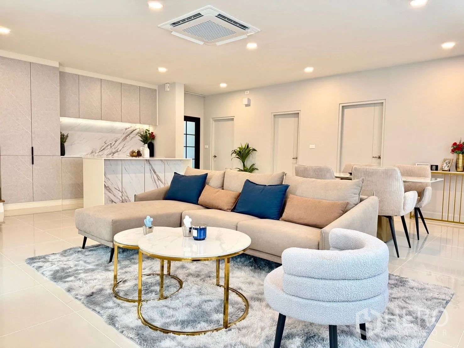 Detached House for rent in Bang Phli, Samut Prakan - Lounge with sectional sofa, nested round coffee tables, and view to sleek kitchen.