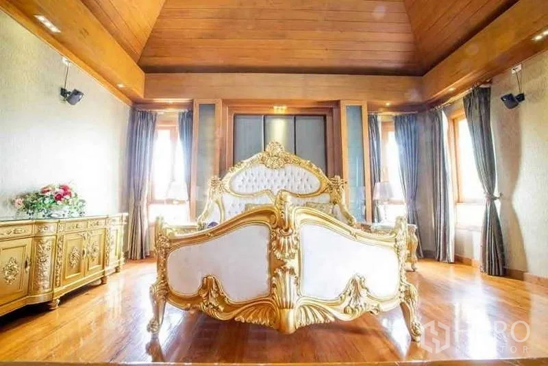 Detached House for sale in Bueng Kum, Bangkok - Opulent bedroom with gold carved bed, wood ceiling and ample windows.