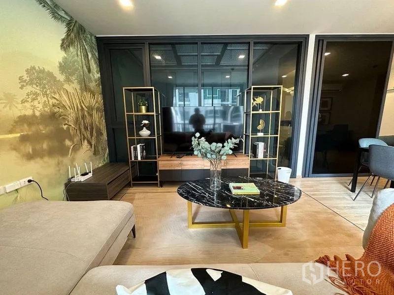 公寓 出租在Ratchathewi, Bangkok - 电视墙配金色开放置物架、风景壁画和黑色大理石茶几。