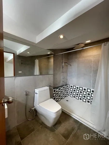 Townhouse for rent in Khlong Toei, Bangkok - Bathroom with walk-in shower, checkered tile trim and modern toilet.