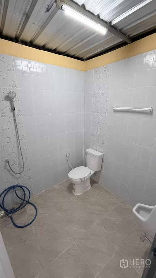 Warehouse for rent in Wang Thonglang, Bangkok - Clean tiled bathroom with shower, toilet, and ceiling light inside the warehouse.