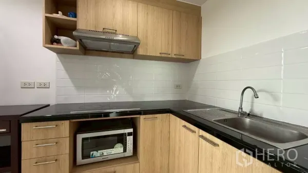 คอนโด ขายในYan Nawa, Bangkok - ครัวบิลท์อิน ตู้ไม้ เคาน์เตอร์สีดำ เตาไฟฟ้า และผนังกระเบื้องสีขาว