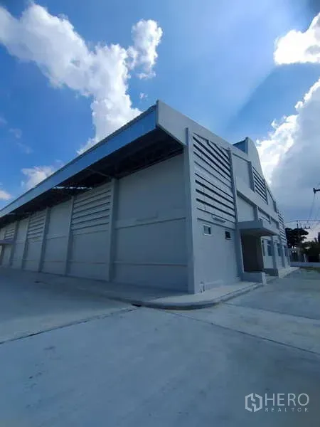 Warehouse for rent in Bang Pakong, Chachoengsao - Corner view of the warehouse showing metal roof, ventilation panels and loading bays.