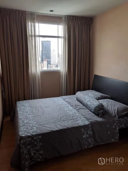 Condominium for rent in Watthana, Bangkok - Second bedroom with double bed and tall window showcasing a city skyline view.