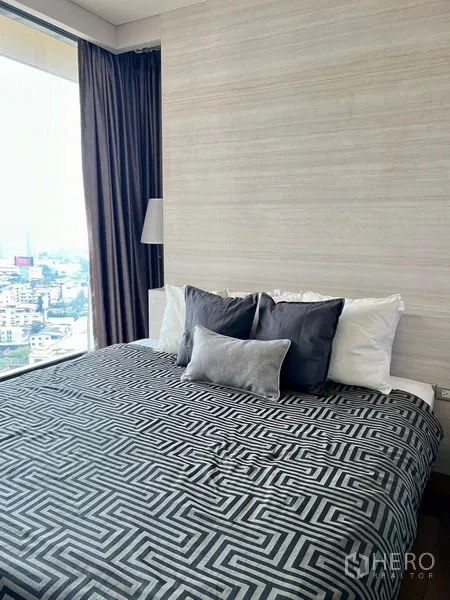 คอนโด ให้เช่า - ห้องนอนหน้าต่างบานใหญ่ ผ้าคลุมเตียงลายกราฟิก ผ้าม่านทึบ พร้อมวิวสกายไลน์เมือง