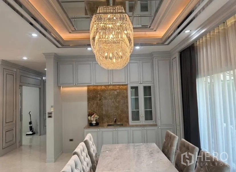 บ้านเดี่ยว for rent or sale in Prawet, Bangkok - มุมมองห้องทานอาหารกับโคมไฟเด่น ตู้กระจก และผ้าม่านเต็มความสูง