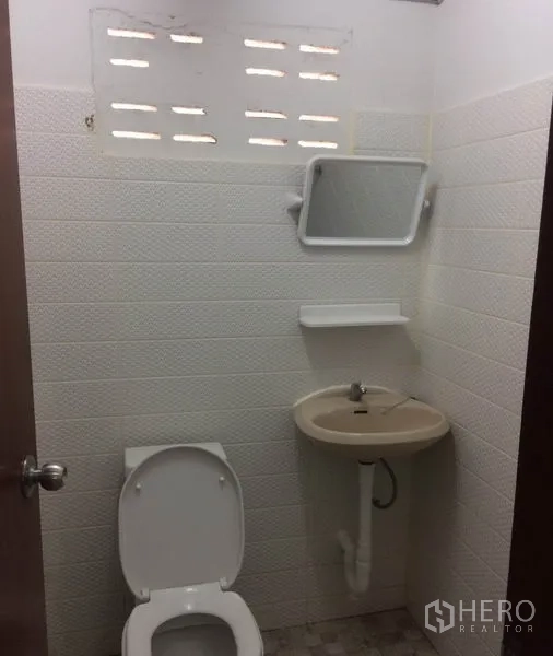 货栈 出租在Pathum Thani - 简洁卫生间，配马桶、洗手盆与通风砖，位于仓库内。