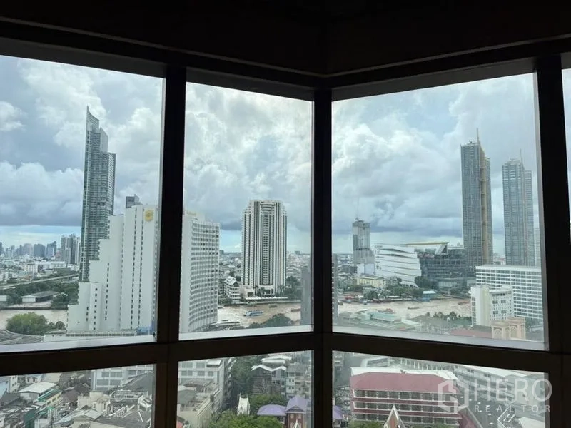 Condominium for rent in Bang Rak, Bangkok - Panoramic skyline and river outlook from corner windows on a cloudy day.