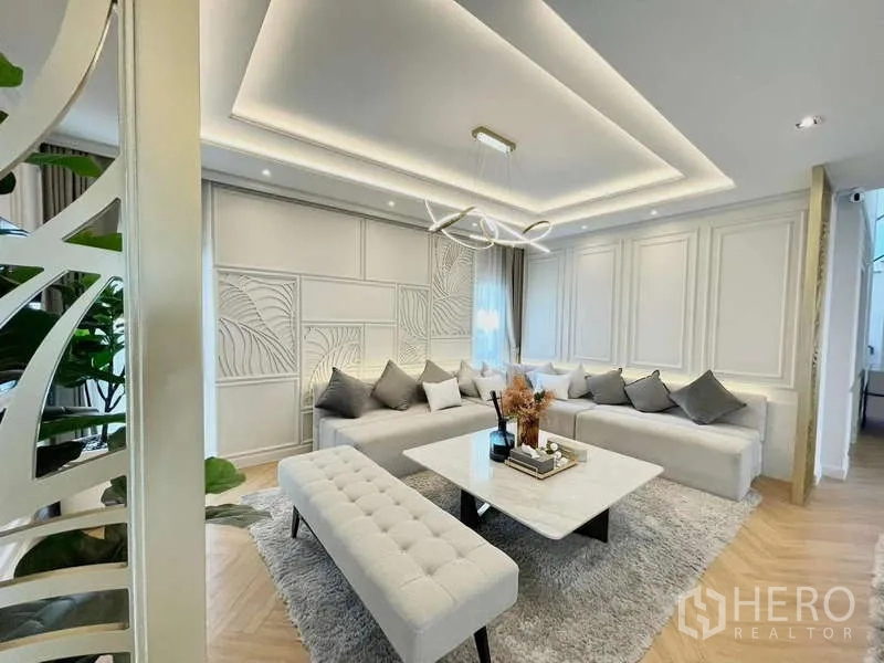 Detached House for rent in Bang Phli, Samut Prakan - Living room with oversized sectional sofa, coffered ceiling and modern lighting.