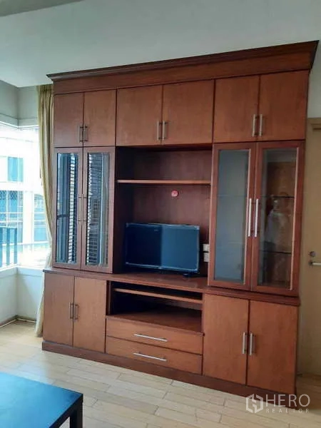 公寓 出租在Khlong Toei, Bangkok - 高大的木质内置电视柜，带玻璃门。