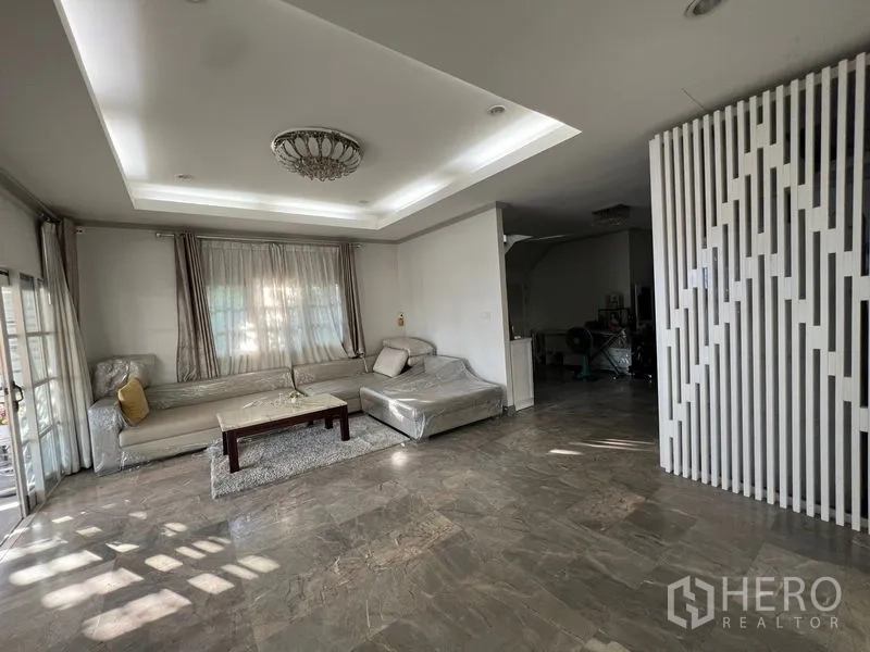 บ้าน ขายในLat Krabang, Bangkok - ห้องรับแขกฝ้าเพดานหลุม ปูพื้นหินสีเทา พร้อมโซฟาเข้ามุม