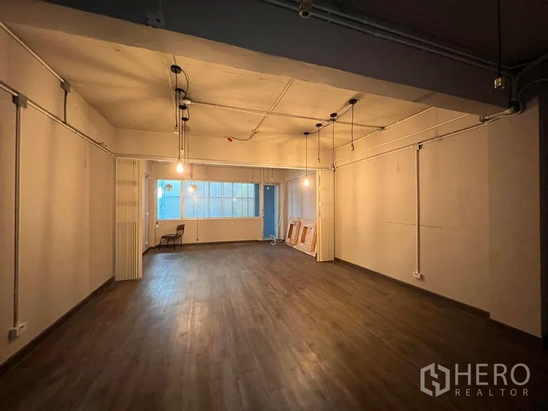 店屋 出租 - 带窗的大型可变空间，木地板与暖色照明。