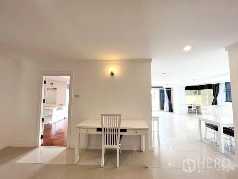 คอนโด ให้เช่าในWatthana, Bangkok - พื้นที่โอเพ่นแพลน พื้นกระเบื้อง โต๊ะทำงานสีขาว และประตูเชื่อมไปยังห้องพื้นไม้