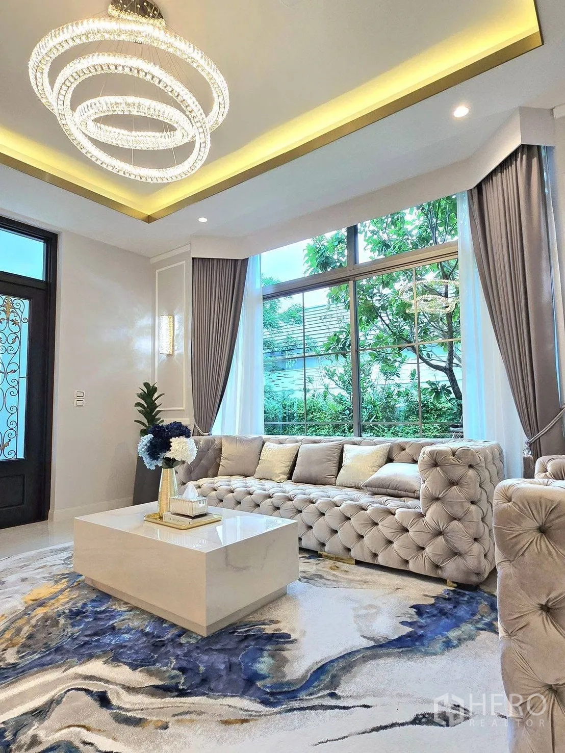Detached House for rent or sale in Bang Phli, Samut Prakan - Elegant living room with tufted sofa set, ring chandelier, marble coffee table and garden-view windows.
