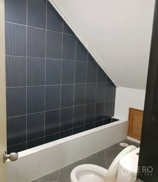 店屋 出租在Watthana, Bangkok - 卫浴间，斜顶设计，深色墙砖与内置浴缸。