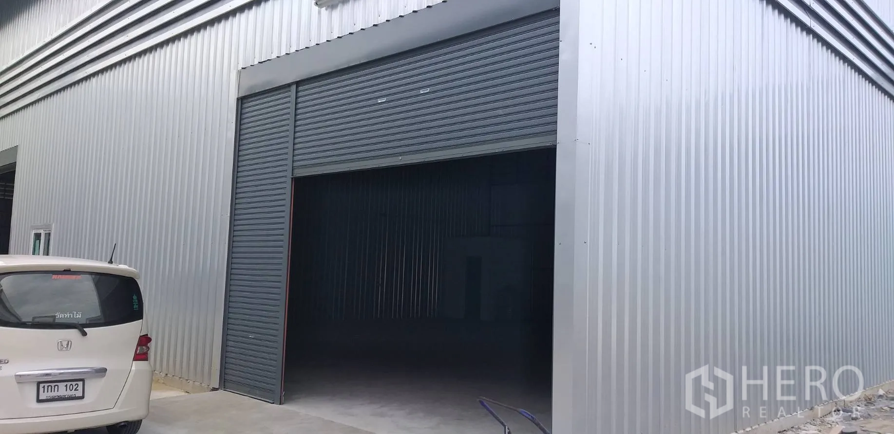 คลังสินค้า ให้เช่าในBang Phli, Samut Prakan - ด้านหน้าโกดังผนังเมทัลชีท ประตูม้วนขนาดใหญ่และลานคอนกรีต