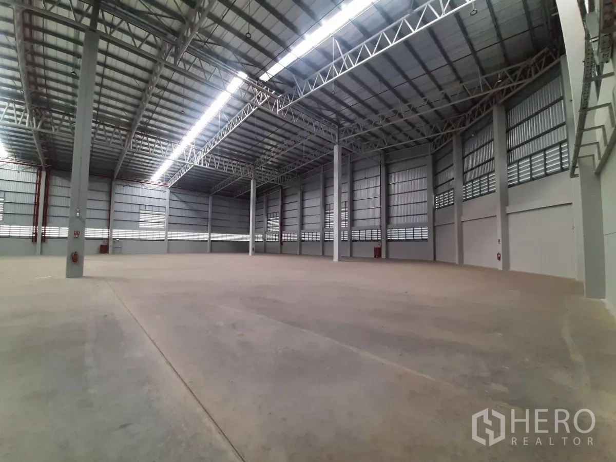 Factory for rent in Bang Lamung, Chon Buri - Open industrial hall with sprinkler pipes and multiple loading doors.
