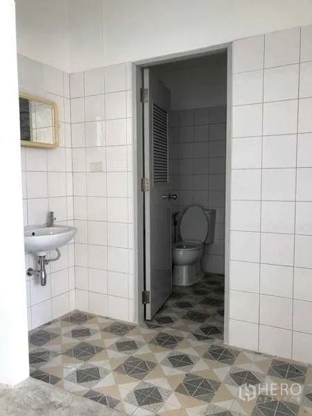 Factory for rent in Khlong Luang, Pathum Thani - Factory restroom with tiled walls, toilet, and hand basin.