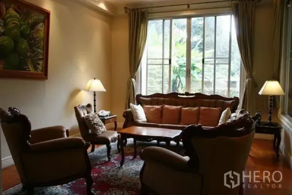 Detached House for rent in Phaya Thai, Bangkok - Cozy sitting room with classic furniture by a large window overlooking the garden.