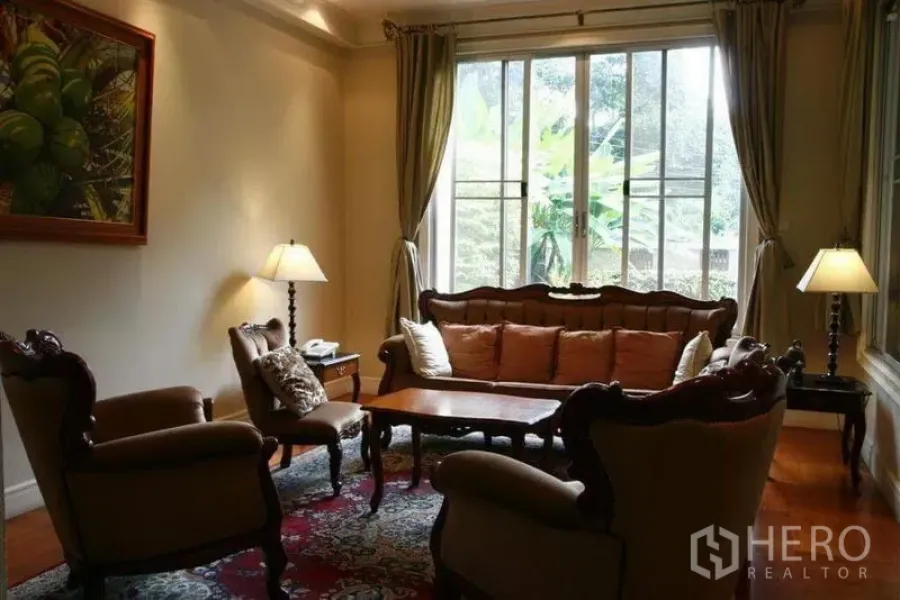 Detached House for rent in Phaya Thai, Bangkok - Cozy sitting room with classic furniture by a large window overlooking the garden.