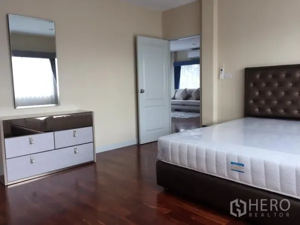 Detached House for rent or sale in Saphan Sung, Bangkok - Secondary bedroom with bed, dresser and warm wood flooring.