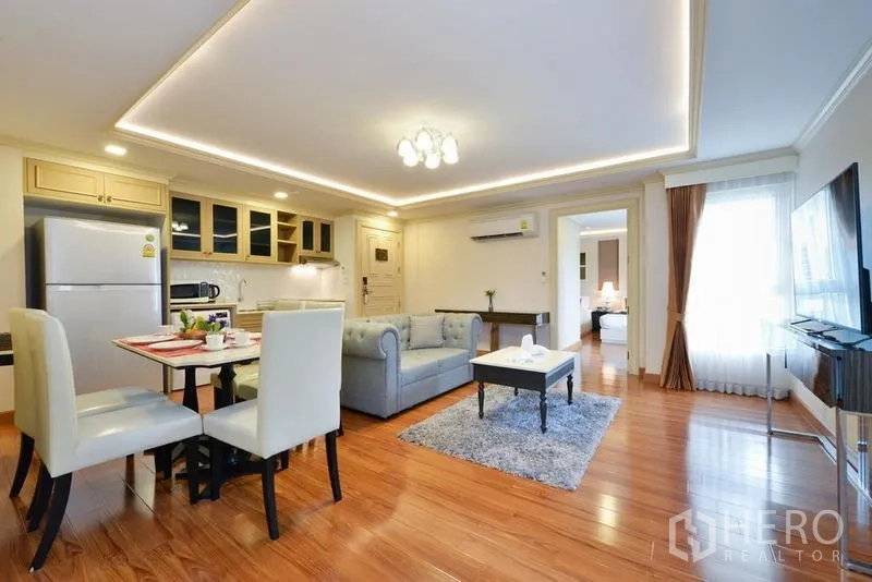 Apartment for rent in Khlong Toei, Bangkok - Spacious living and dining area with large windows, TV and LED ceiling lights.