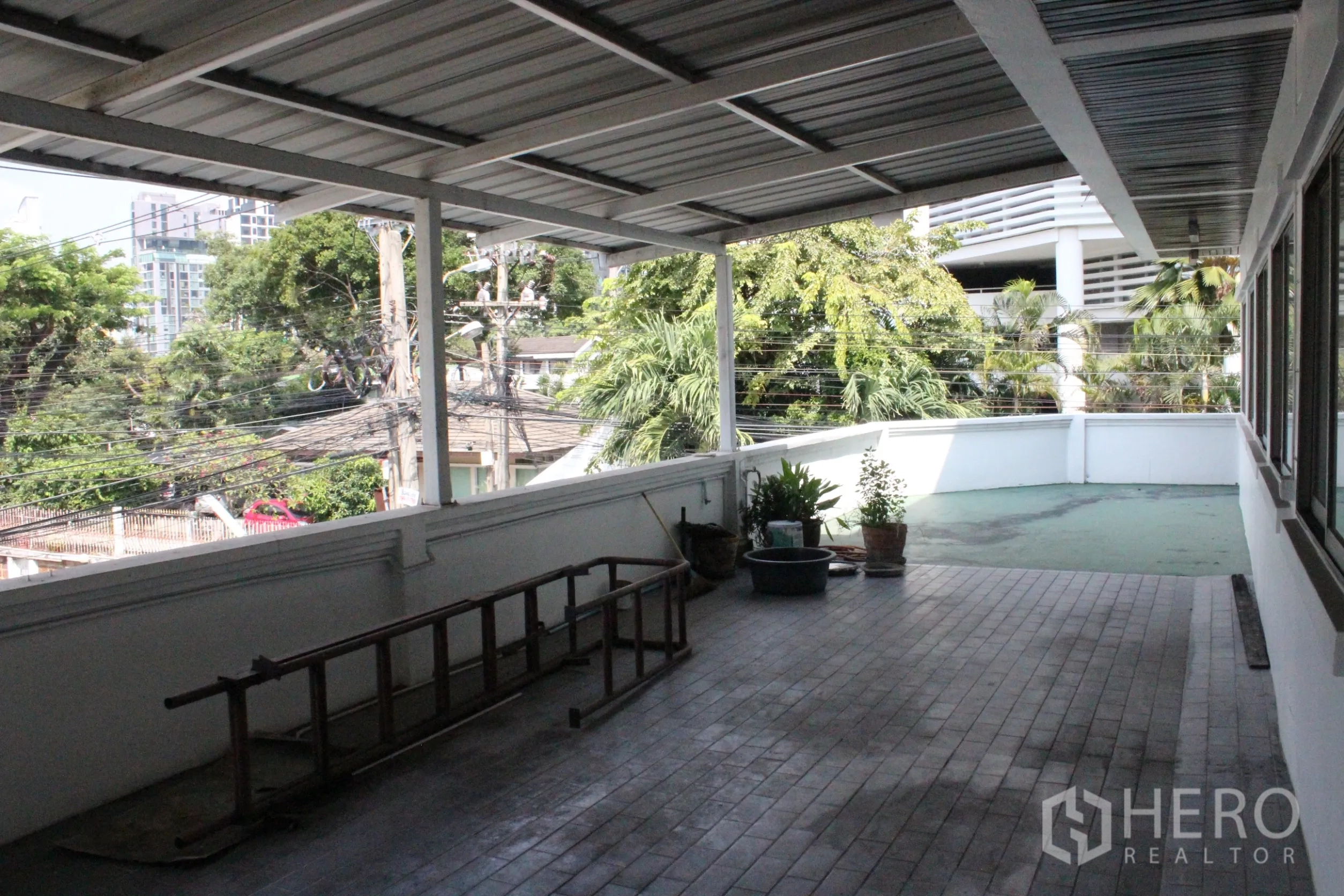 Home Office for rent in Khlong Toei, Bangkok - Wide covered balcony with planters and access to an open terrace overlooking the neighborhood.