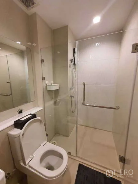 Condominium for rent - Bright bathroom featuring a glass-enclosed walk-in shower and toilet in neutral tones.