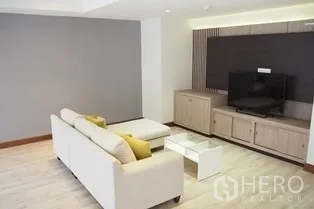 Condominium for rent in Pathum Wan, Bangkok - Bright condo lounge with white sofa, ottoman and media cabinet.