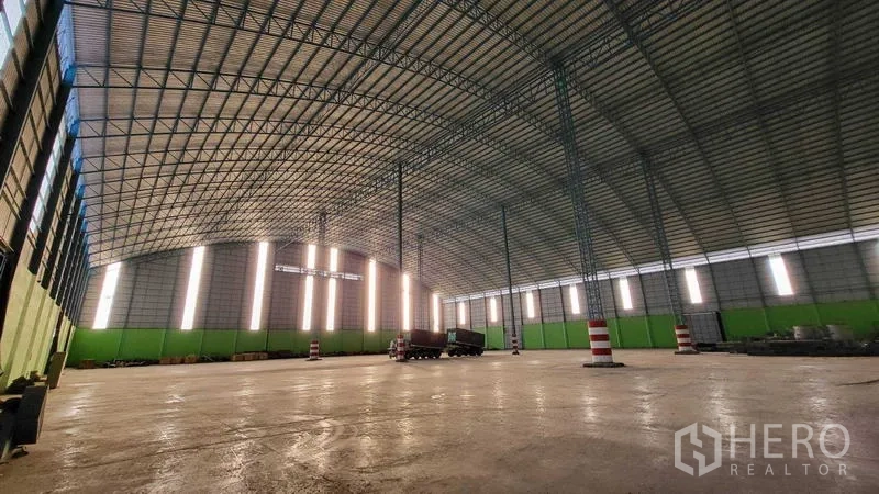 工厂 出租在Sai Noi, Nonthaburi - 全景内部视角，钢桁架屋顶与红白相间立柱，空间宽敞。