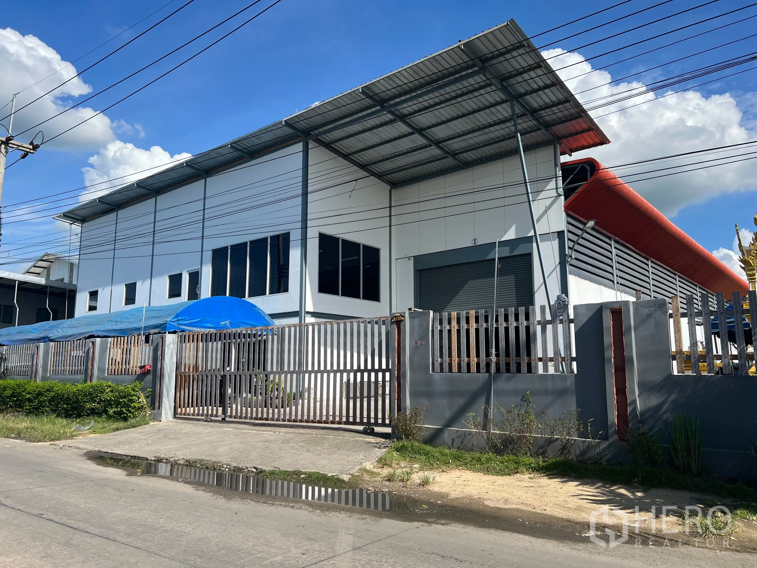 货栈 出售在Lam Luk Ka, Pathum Thani - 蓝武甲县现代白色仓库外观，金属屋顶、卷帘门与安全围栏。