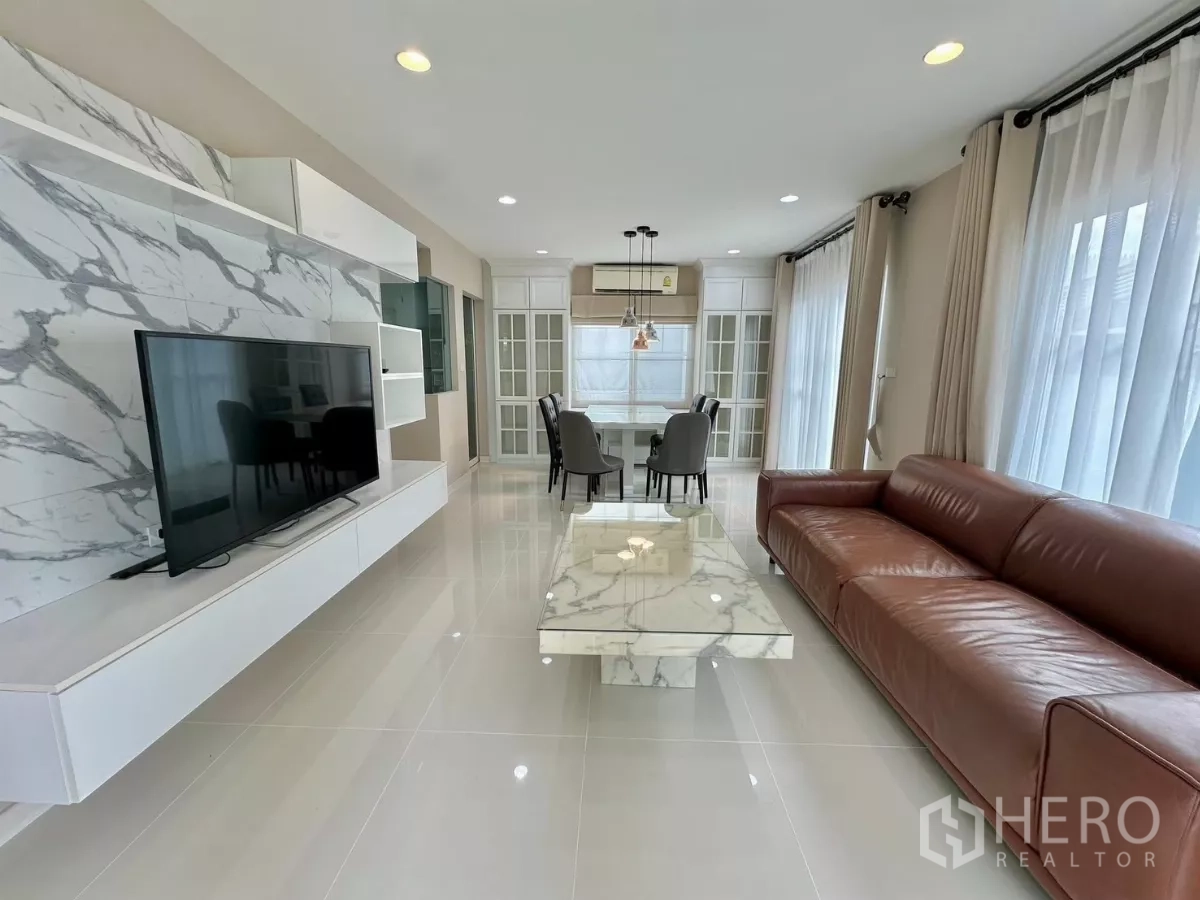 Detached House for rent in Bang Phli, Samut Prakan - Bright living room with marble feature TV wall, leather sofa and full-height windows.