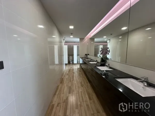 办公空间 出租 - 宽敞洗手间走廊，多个台盆与镜面，柔和照明。