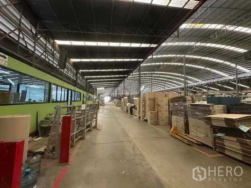 Factory for rent in Pathum Thani - Long internal lane beside glazed offices and stacked cartons ready for dispatch.