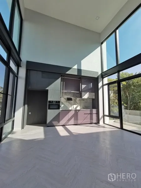 Detached House for sale in Saphan Sung, Bangkok - Open-plan kitchen with high ceilings and a wall of glass overlooking greenery.