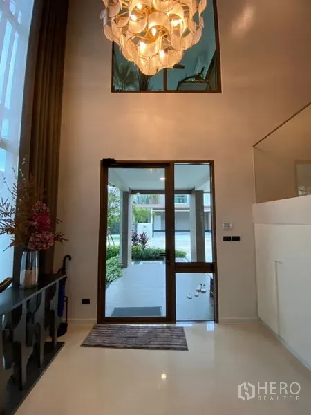 บ้าน ขายในBang Kapi, Bangkok - โถงทางเข้าโปร่งสว่าง ประตูกระจก เพดานสูง และคอนโซล มองสู่สวนหน้าบ้าน