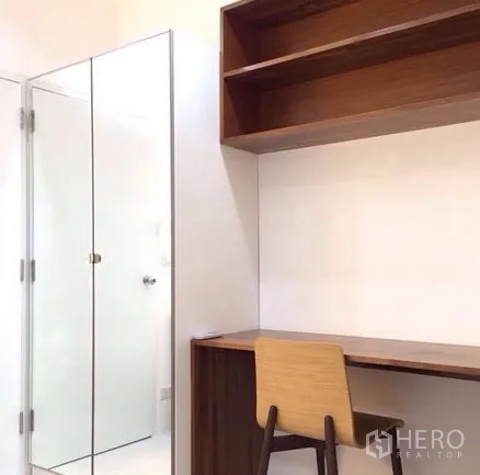 Condominium for rent in Bang Rak, Bangkok - Study nook with wooden desk, overhead shelving and a glass-door wardrobe.