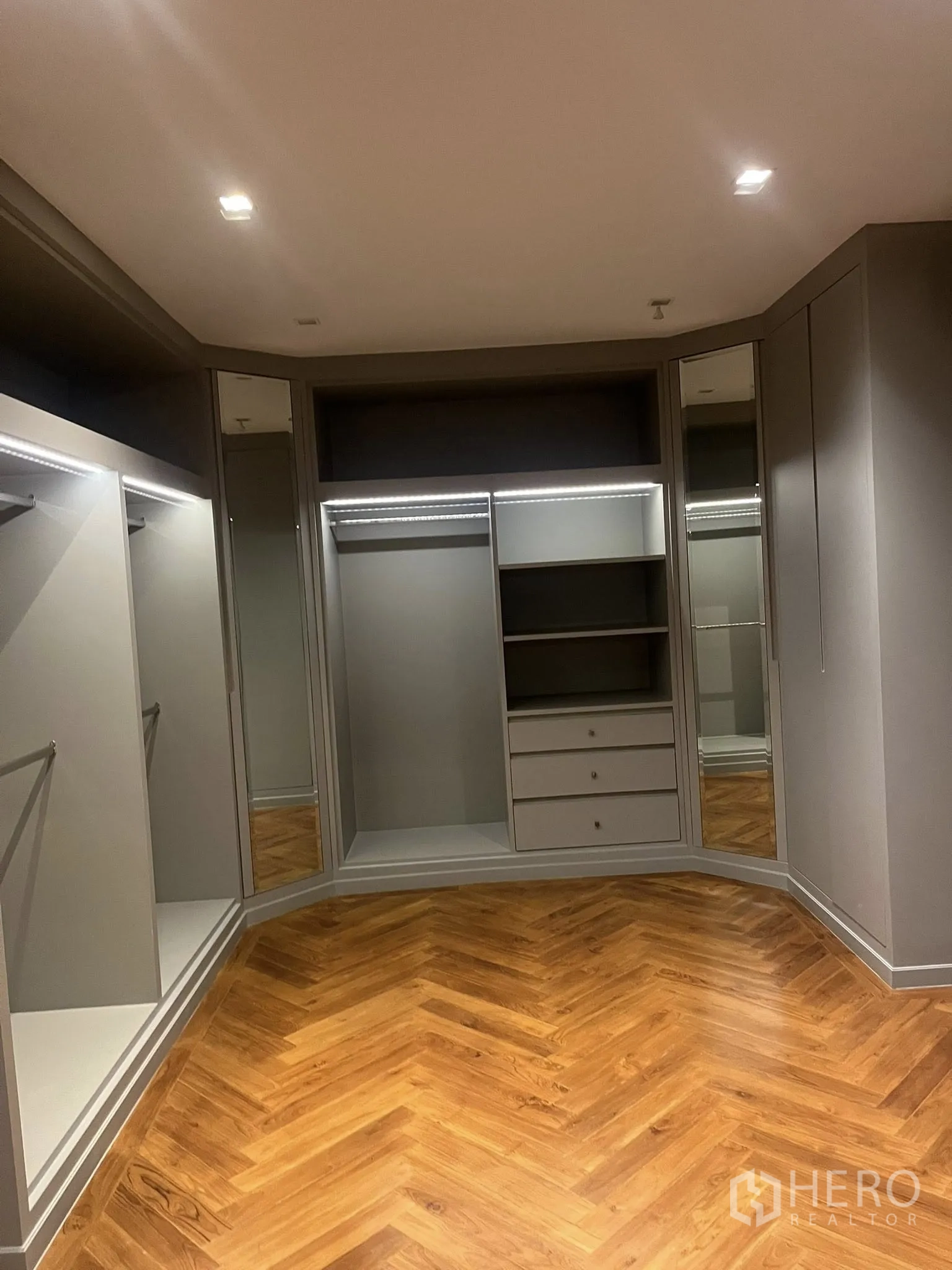 Home Office for rent in Watthana, Bangkok - Walk-in closet with open shelving, hanging rails, and herringbone wood flooring.