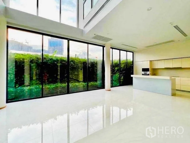 บ้าน ขายในHuai Khwang, Bangkok - ห้องนั่งเล่นเพดานสูงโปร่ง ผนังกระจกเต็มบาน พร้อมครัวไอส์แลนด์ มองเห็นสวนแนวรั้ว