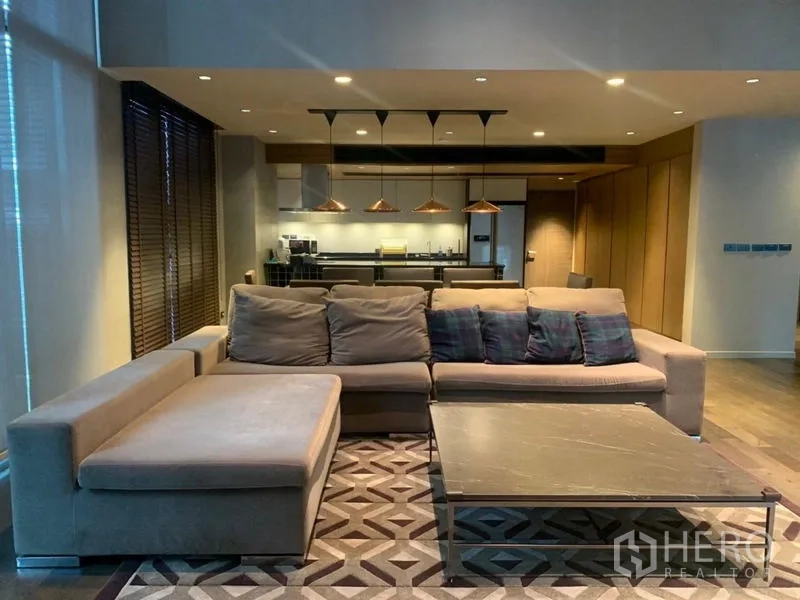 คอนโด ให้เช่าในWatthana, Bangkok - พื้นที่นั่งเล่นกว้าง โซฟาเซ็ตใหญ่ โต๊ะกลางหินอ่อน และมุมครัวด้านหลัง