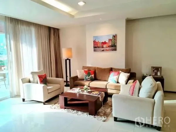 อพาร์ทเมนท์ ให้เช่า - ห้องนั่งเล่นสว่างพร้อมโซฟาชุด โต๊ะกลาง และผ้าม่านสูงจรดเพดาน