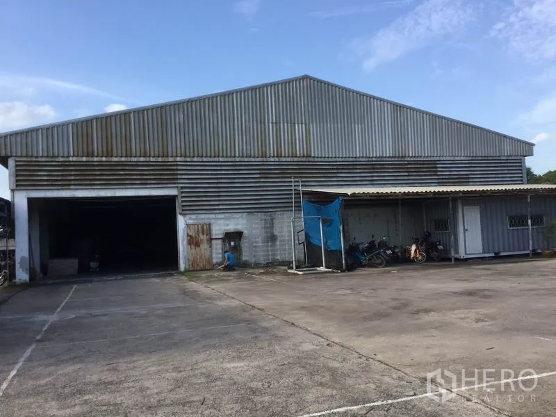 Warehouse for sale in Sai Noi, Nonthaburi - Metal-clad warehouse exterior with wide loading bay and concrete driveway in Sai Noi.