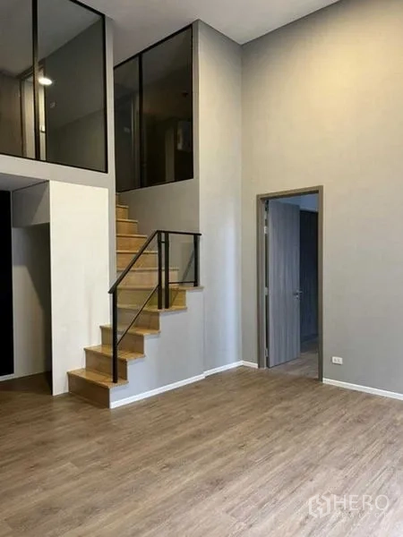 Condominium for sale in Huai Khwang, Bangkok - Spacious living area with stairway and a separate bedroom door.