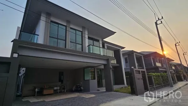 บ้าน ให้เช่าหรือขายในPrawet, Bangkok - หน้าบ้านเดี่ยวสองชั้นสไตล์โมเดิร์น ระเบียงกระจก ที่จอดรถในร่ม บรรยากาศถนนเงียบยามเย็น