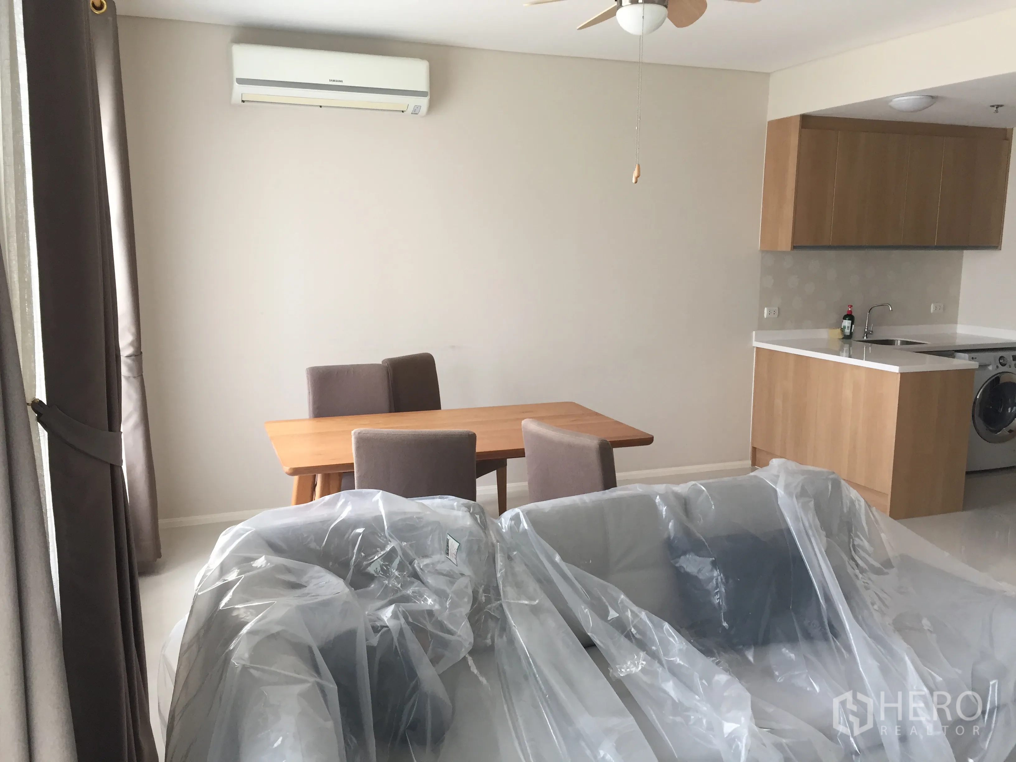 คอนโด ให้เช่าในRatchathewi, Bangkok - โถงนั่งเล่นแบบโอเพ่นสเปซ พร้อมโต๊ะทานข้าว ติดกับครัวบิลท์อินลายไม้และเครื่องปรับอากาศ