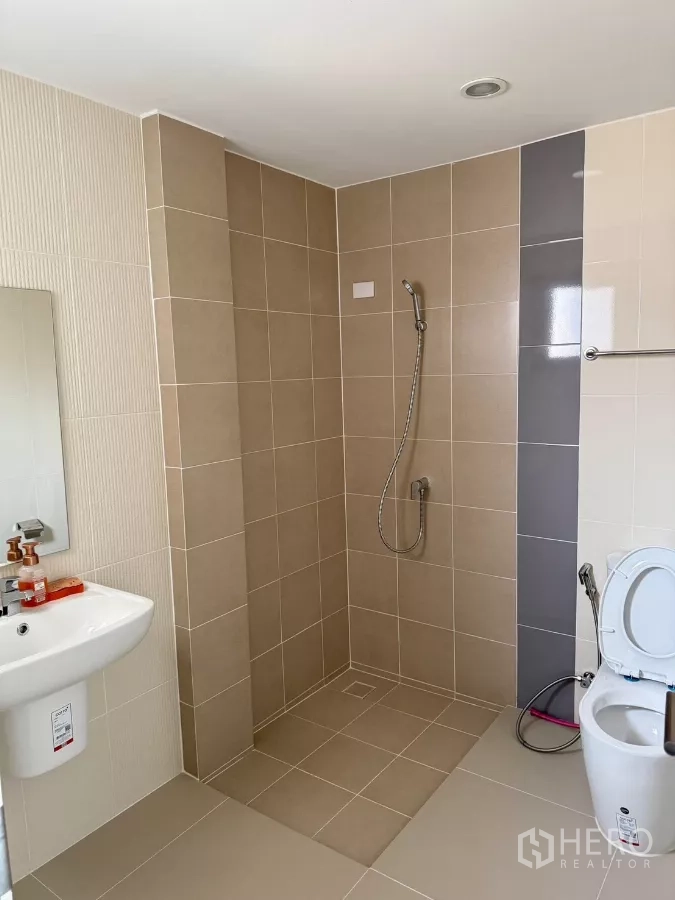 บ้าน ให้เช่าในSaphan Sung, Bangkok - ห้องน้ำกว้าง โซนฝักบัวแบบวอล์กอิน กระเบื้องโทนเบจ โถสุขภัณฑ์ และอ่างล้างหน้าแขวนผนัง